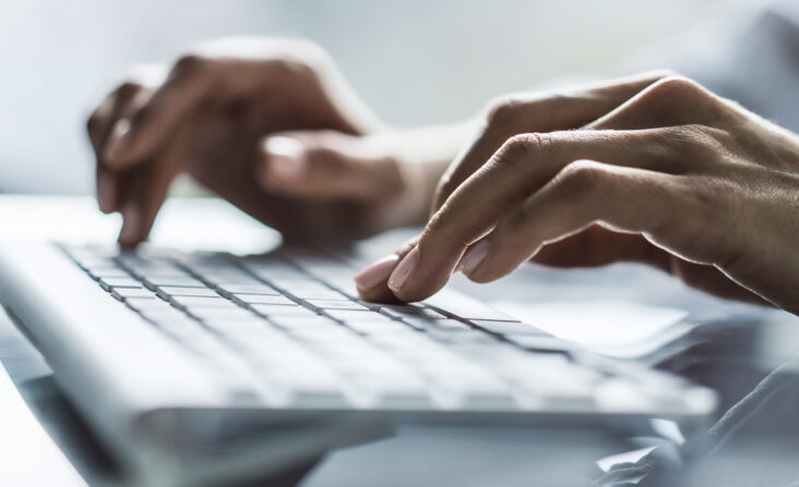 What To Do If You Are Facing Workplace Discrimination - Woman types on a computer keyboard in a sunny office, close up